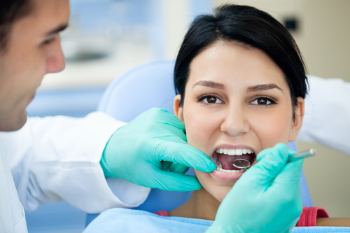 Female patient having her teeth examined by dental specialist